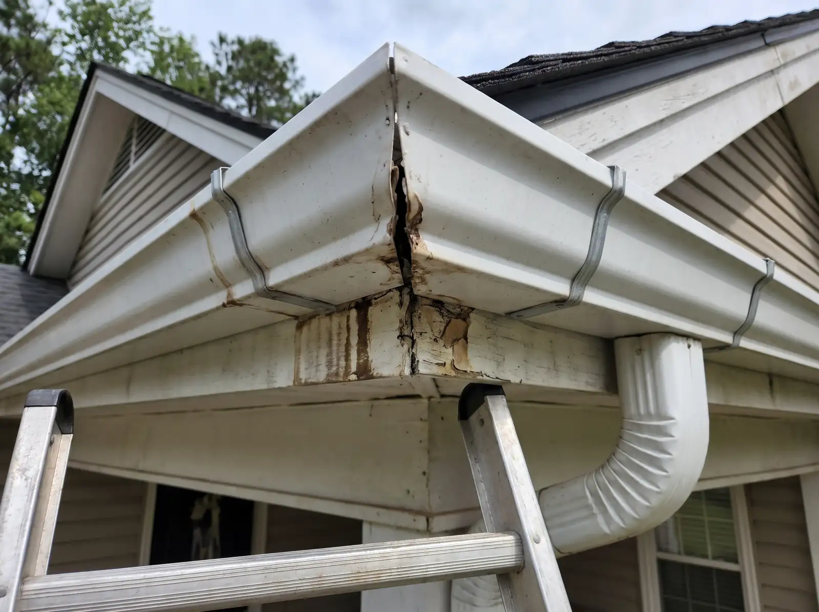 Split outside gutter corner with rust and water stains on the fascia below